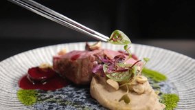 Final touch in dish serving. Cooking process. Rotating dish. Luxury restaurant. Chef finishing duck dish with salad leaf. Serving plate with micro greens. final ingredients. restaurant kitchen. Full - Powered by Shutterstock - Get 15% off with code: PIKWIZARD15