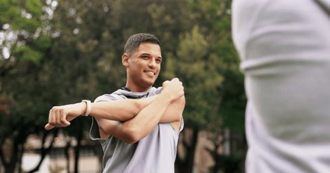 Fitness stretching, personal trainer and outdoor of an athlete talking before sports and workout. Arm stretch, warm up and exercise of a male runner in a park for running training with client Video Stok