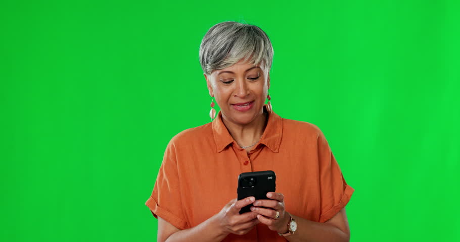 Senior woman, phone and celebration on green screen for winning, prize or competition against studio background. Happy and excited elderly female dancing or jumping in joy for good news on smartphone