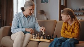 Loving grandmother and adorable granddaughter playing chess at home, sharing happy moments together. Adorable little kid girl learning rules of chess game, engaged in board games with her cute granny - Powered by Shutterstock - Get 15% off with code: PIKWIZARD15
