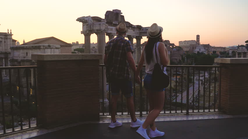 Young couple tourist walking in front of Roman Forum at sunrise. Historical imperial Foro Romano in Rome, Italy from panoramic point of view. Royalty-Free Stock Footage #1102576769
