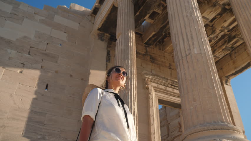 Young Woman visiting Parthenon, Acropolis of Athens, Greece. Large hat, fashion white dress, sunglasses, vintage camera. Royalty-Free Stock Footage #1102576799
