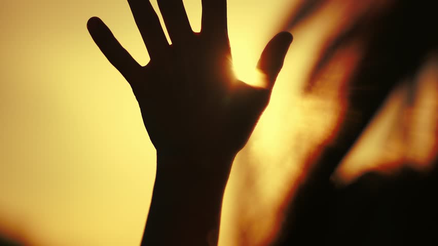 hand of happy girl at sunset with glittering golden light. sunset between the hands of girl. this happy girl stretches her hand to the sun. girl silhouette stretches dream out her hand to the sun Royalty-Free Stock Footage #1102577025