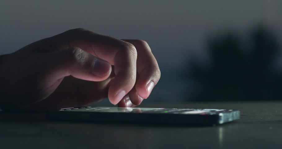 Close-up hands of a man scroll news feed on mobile phone. Screen of the mobile phone illuminates male hand. Close-up of the male use the mobile phone at night. Scrolling social networks. Royalty-Free Stock Footage #1102582113