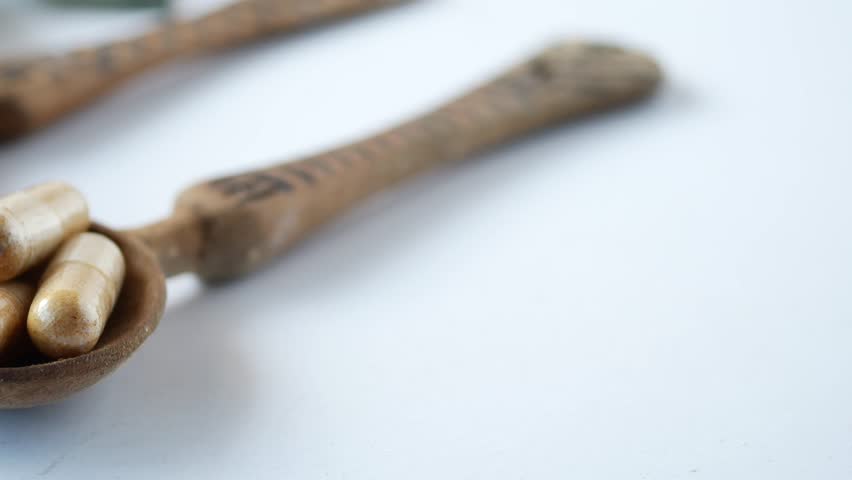 herbal medicine capsule and powder on spoons 