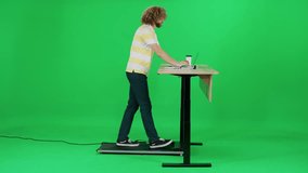 Standing work, passer-by man in office walking on a green background and uses a laptop, man enjoy a walk and works at the lifting table, a man on a treadmill, chromakey. - Powered by Shutterstock - Get 15% off with code: PIKWIZARD15