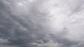 Time lapse 4k video of flying fast grey cumulus clouds high in sky. Cloudy fluffy rainy dramatic cloudscape timelapse. Stormy grey and white cloudscape, black silhouettes of flying birds