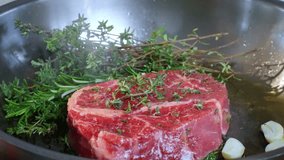 Food preparation. Chef cooks beef steak, Chef ad salt over steak. Preparing food in kitchen Selective focus. Slow motion video.
