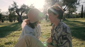 closeup slow motion of two girls couple lesbian homosexual lgbt talking and kissing in a park with sunbeams