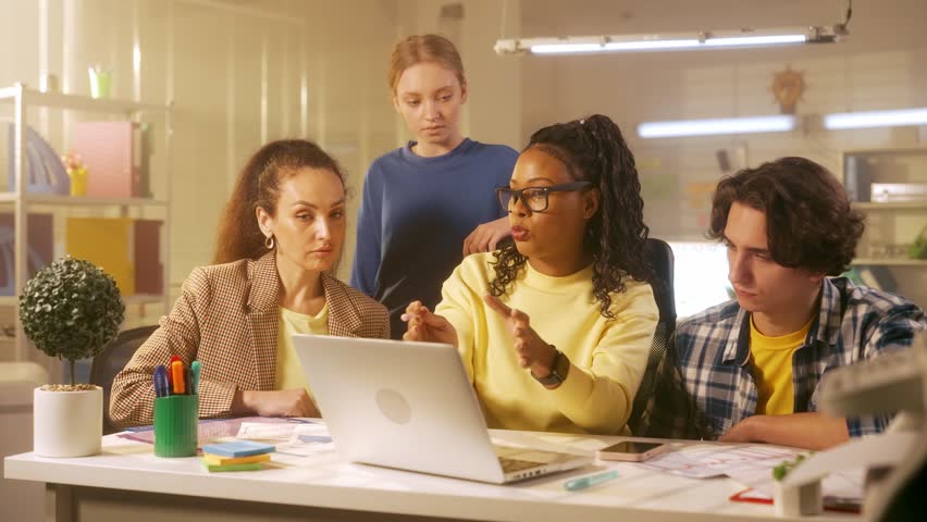 African American woman leader of the group tells his employees about the new project and makes a presentation on a laptop. Young creative team of managers or startups work together in the office.