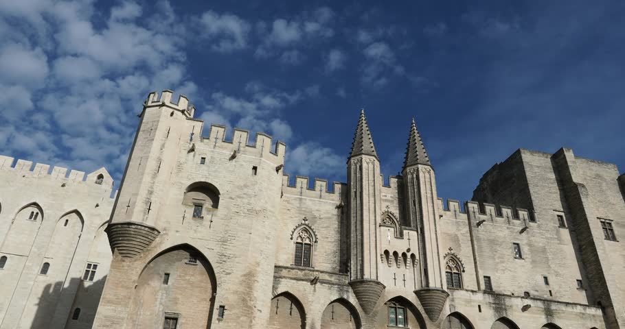 Clouds moving in a blue sky over the iconic façade of Palais des Papes in Avignon, France, Unesco World Heritage Site