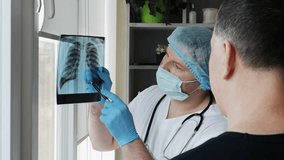 A doctor in an office with a sick patient, a radiographer examines an x-ray of the lungs of an elderly person in a hospital. The doctor diagnoses pneumonia. X-ray in the hands of a male doctor - Powered by Shutterstock - Get 15% off with code: PIKWIZARD15