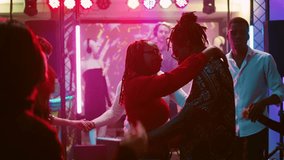 Group of friends partying at nightclub, partying on music with DJ on stage and colorful spotlights. Happy people enjoying modern party, dancing for entertainment. Handheld shot. - Powered by Shutterstock - Get 15% off with code: PIKWIZARD15