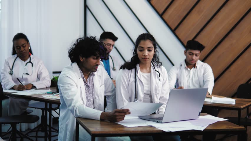 General practitioner speaking about new methods of treatment during medical training class, medical students don't understand, ask questions, raise hands, show picture document. Students at lecture  Royalty-Free Stock Footage #1102599929