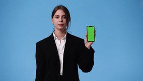 4k video of one girl who showing something on the phone over blue background.