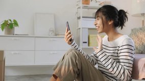 Young asian woman sit using mobile phone enjoying video call with friend on smartphone ,while sunlight  her face in the evening.