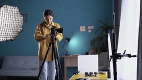 Female photographer setting up camera in home studio. Professional photographer on fashion shoot in photo studio with lighting equipment - Powered by Shutterstock - Get 15% off with code: PIKWIZARD15