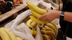 Close-up of a woman choosing bananas in a supermarket. Caring mother and wife shopping at the grocery store. - Powered by Shutterstock - Get 15% off with code: PIKWIZARD15