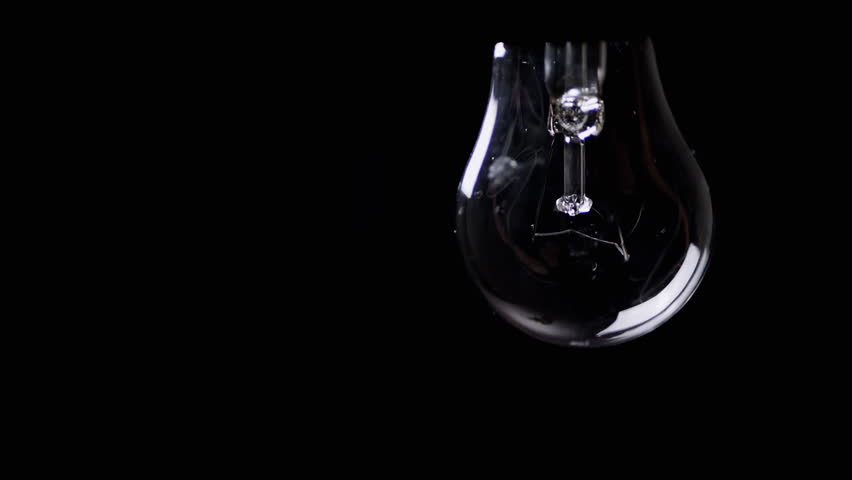 Hanging Swinging flickering Light Bulb in a Dark Room on the Black Background. Old Edison tungsten incandescent shining on and turning off. Energy crisis. Electricity. Power outage. Blackout. Change. Royalty-Free Stock Footage #1102610641