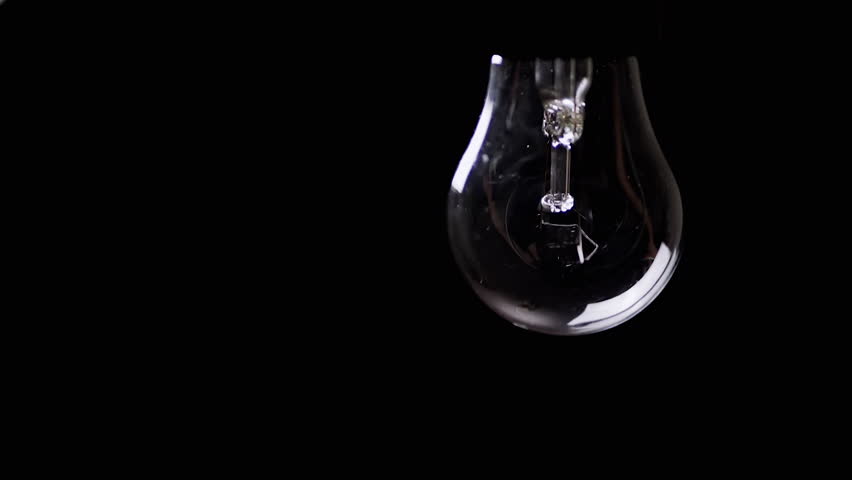 Hanging Swinging flickering Light Bulb in a Dark Room on the Black Background. Old Edison tungsten incandescent shining on and turning off. Energy crisis. Electricity. Power outage. Blackout. Change. Royalty-Free Stock Footage #1102610659