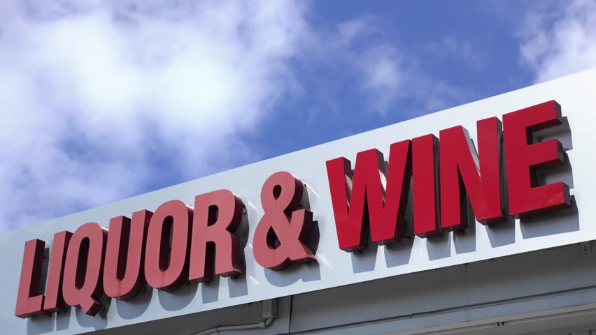 A Sign For A Liquor And Wine Store Against A Bright Blue Sky