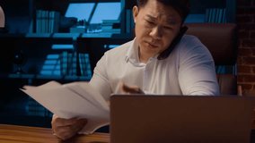 Tired angry Asian business man talking mobile phone at night evening office check documents working laptop overworked stressed Korean businessman executive manager arguing with call computer paperwork - Powered by Shutterstock - Get 15% off with code: PIKWIZARD15