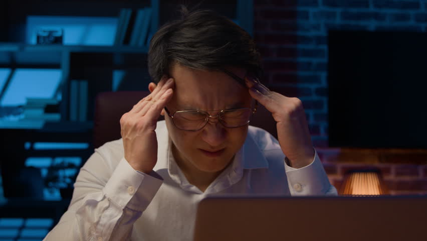 Stressed Asian businessman in glasses working with laptop at night in home office exhausted ill tired Korean middle-aged man overworked executive feel headache pain migraine stress business failure | Shutterstock HD Video #1102614147