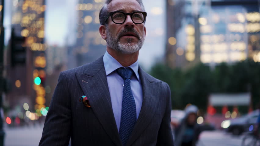 Adult and successful business man in expensive suit, stylish eye glasses walks down street in financial district, he feels confident. 50 years old entrepreneur with gray hair walk in evening city Royalty-Free Stock Footage #1102614981