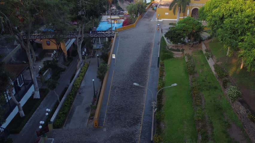 Drone hovers and slowly tilts up camera revealing to the left a bridge called "Puente de los suspiros" and to the right a church called "Iglesia La Ermita" Located in Barranco district of Lima, Peru.