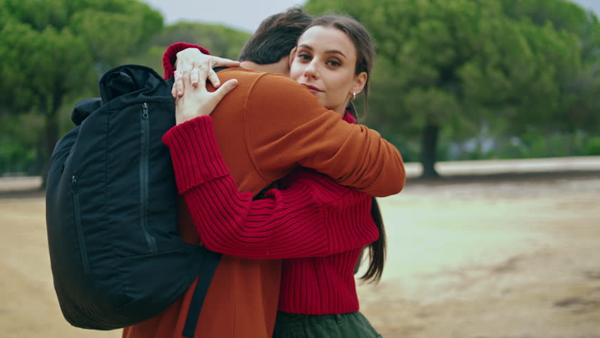 Happy young family embracing on nature enjoy closeness close up. Couple relaxed tourists standing near autumn forest hugging. Carefree relaxed hikers feeling calmness hapiness on trip together.