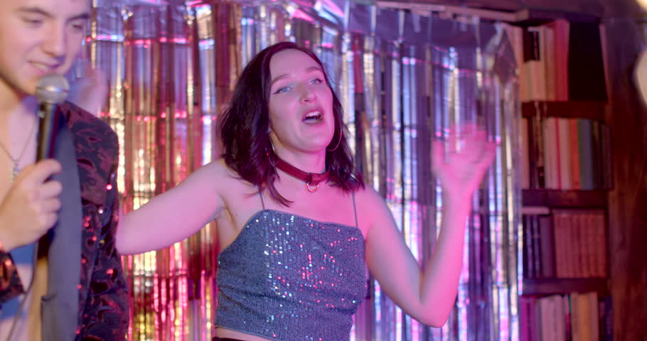 Inspired girl waving a red scarf in her hands at a party, she draws attention to herself. Camera and light movement in bokeh.