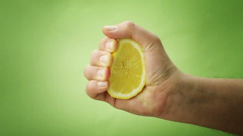 hand squeezing lemon on green background - 1080p Stockvideó