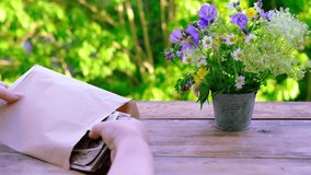 female hands holding paper envelope with old photographs, bouquet of wild flowers on table wooden table in garden, blurred natural background, concept of genealogy, memory of ancestors, family tree - Powered by Shutterstock - Get 15% off with code: PIKWIZARD15