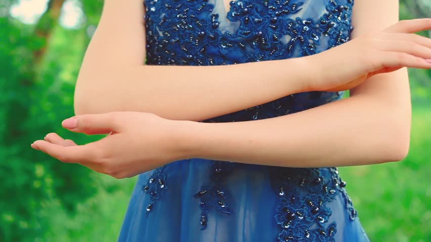 Young brunette young woman touches skin with hands fingers close-up Fashion model girl sexy strokes herself neck face shoulders. Evening Hairstyle romantic blue dress. Summer nature green trees park
