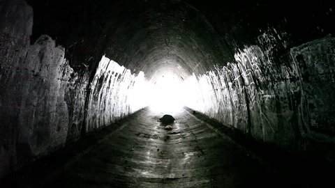 Urban tunnel explorer walking out of the light.