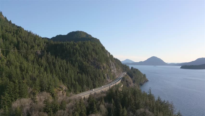 Aerial View of Sea to Sky Highway in Howe Sound. Sunny Sunset Sky. Between Squamish and Vancouver, BC, Canada. Royalty-Free Stock Footage #1102639009