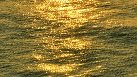 As the sun begins to rise above the horizon, its golden light illuminates the world below, creating a breathtaking view of glistening orange waves from an aerial perspective captured by a drone. 4K
