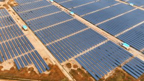 A sprawling field of photovoltaic cells arranged in rows, the solar power plant appears as a shimmering blue grid. Industrial concepts and technologies for the environment. Aerial view drone. 4K HDR
