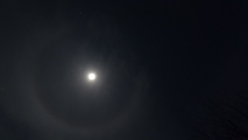 Time lapse moon with stars, bright glow around the moon and clouds flying by. Bright night sky