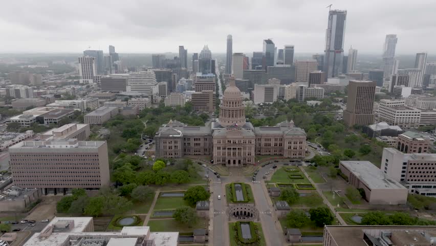 Texas state capital building with Austin, Texas skyline and drone video moving in a circle.