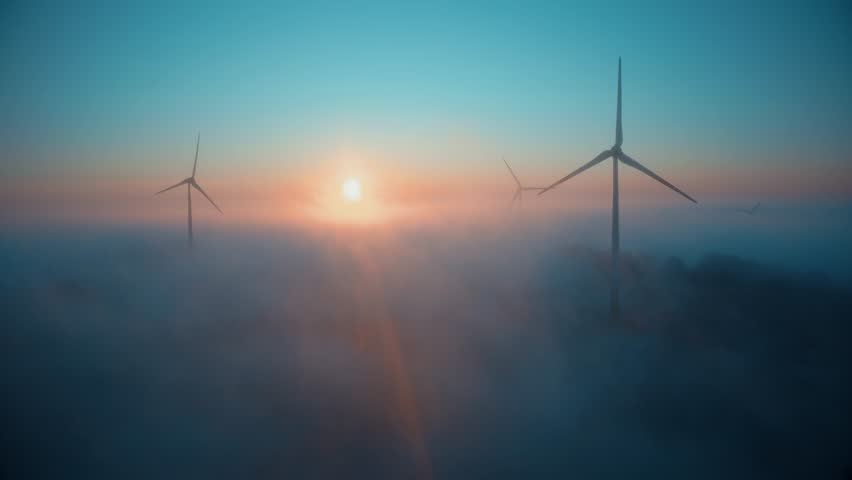 Wind farm at sunrise in heavy fog. Wind turbines generating green energy - concept of renewable electricity, sustainable energy