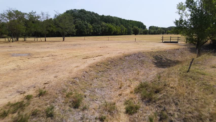 Low flyover above dry ditch in arid field suffering from drought in Hungary.