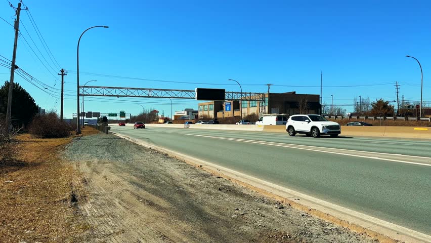 Truck with passenger cars in semi-trailer drives along the freeway exit from the city Dartmouth Canada. Transportation new cars across the country of Canada with the help large truck semi-trailers. 