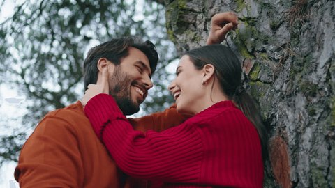Happy smiling couple standing autumn forest leaning on tree close up. Beautiful loving two people talking laughing on nature weekend. Cheerful family enjoy time together feeling love happiness. 庫存影片