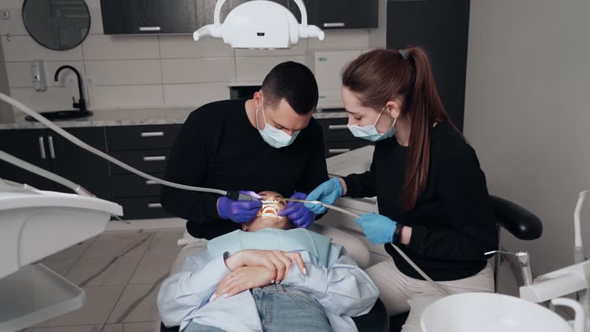 Two doctors, man and woman in protective masks in a dental clinic, serve the patient girl. Work Dentist. Healthcare and medicine concept. Royalty-Free Stock Footage #1102654605