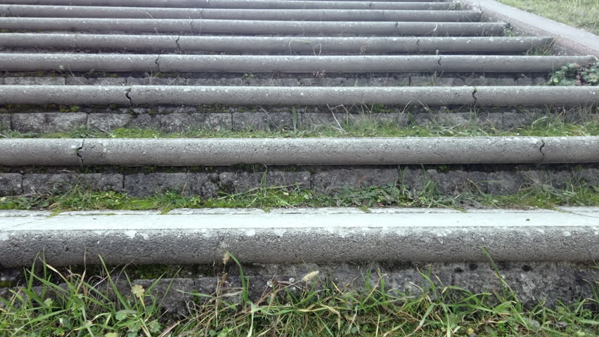 Climbing up concrete stairs with grass in the park POV, closeup