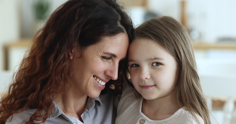 Close up of happy mom and daughter kid hugging with cheek face touches, laughing, turning look at camera with toothy smile, enjoying family bonding, motherhood, childhood, closeness Royalty-Free Stock Footage #1102664613