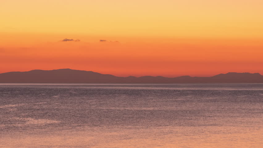 4K time lapse of majestic sunrise scenery. Seascape at dawn. The sun rises, sky changes color from dark orange to bright yellow. Beautiful morning timelapse over the sea. Nature environment background