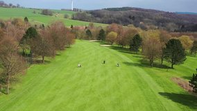 Aerial drone sunset view green golf course in spring. Beautiful golf playground field with hills, sand areas and trees. High quality 4k footage