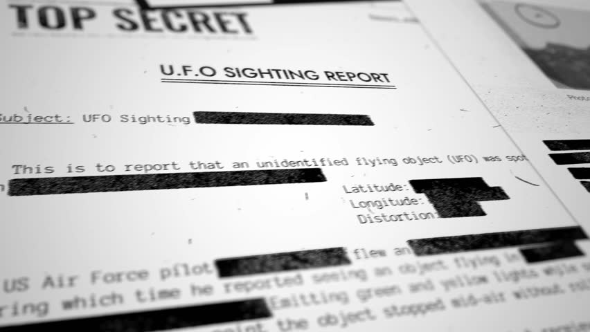 Various top secret and classified looking documents about UFO and alien activity. Camera moves slowly over files and papers with photographs and sensitive information about unidentified phenomenons Royalty-Free Stock Footage #1102673539